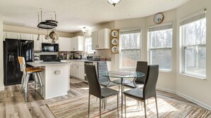 A modern kitchen with a central island, bar stools, and a dining table with chairs. - Indianapolis Rental Home w/ Gym: Near Speedway! (Indianapolis)