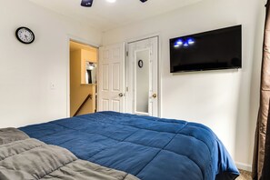 A bedroom with a large bed, a TV mounted on the wall, and a door leading to another room. - Indianapolis Rental Home w/ Gym: Near Speedway! (Indianapolis)