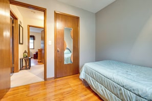 Cozy retreat with a single bed, wooden door, and a small table with a lamp.