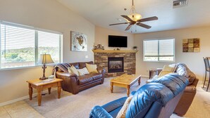 A living room with a fireplace, leather sofas, a flat-screen TV, and a ceiling fan. - 2 Mi to Lake: Apt w/ Balcony in Payson! (Payson)