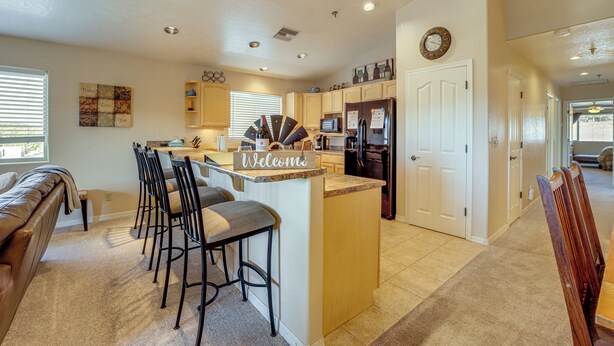 A modern kitchen with a central island, bar stools, and a 'Welcome' sign. - 2 Mi to Lake: Apt w/ Balcony in Payson! (Payson)