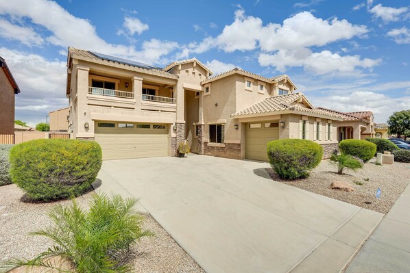 A two-story house with a balcony, a garage, and a well-maintained front yard with shrubs and a gravel path. - Spacious Surprise Vacation Rental Near Phoenix! (Surprise)