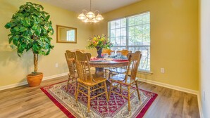 A dining area with a wooden table, four chairs, a potted plant, and a chandelier. - 2 Mi to Uca: Group Getaway w/ Private Yard! (Conway)