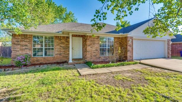 A single-story brick house with a front garage, a front door, and a small front yard with grass and a flower bed. - 2 Mi to Uca: Group Getaway w/ Private Yard! (Conway)