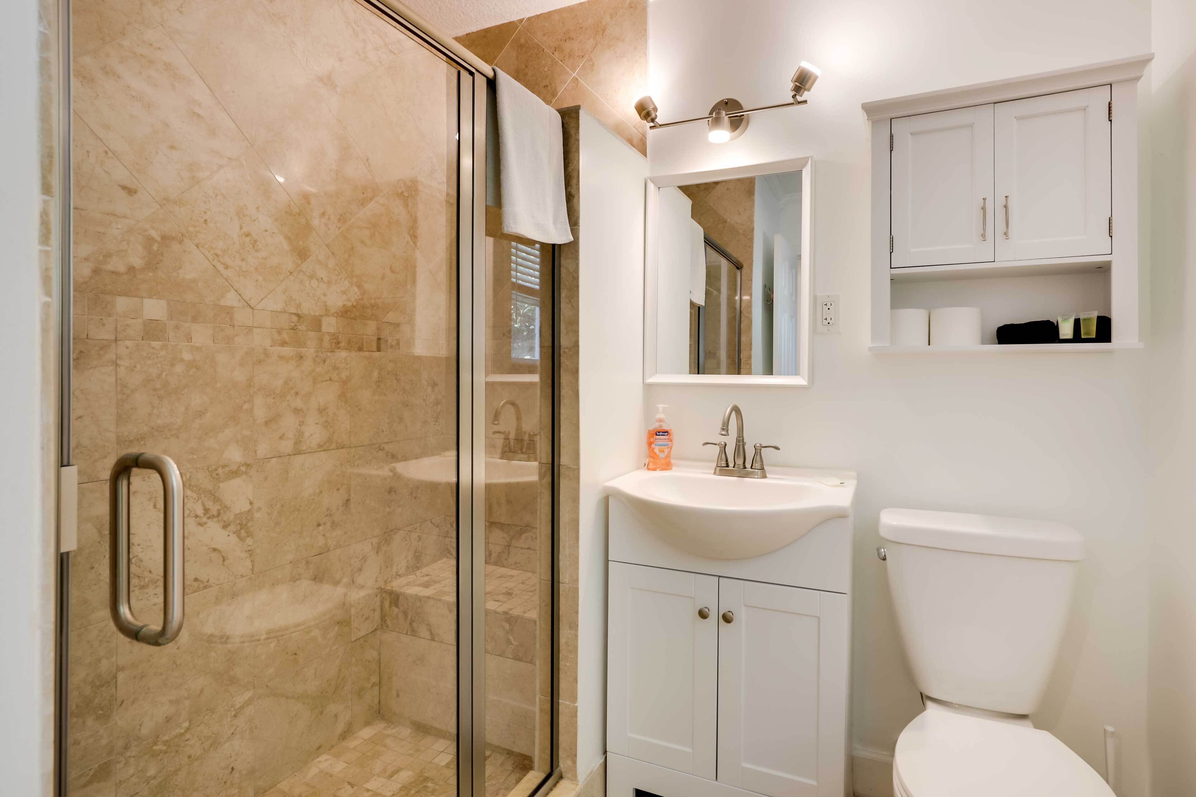 A bathroom with a glass-enclosed shower, a white sink, and a toilet.