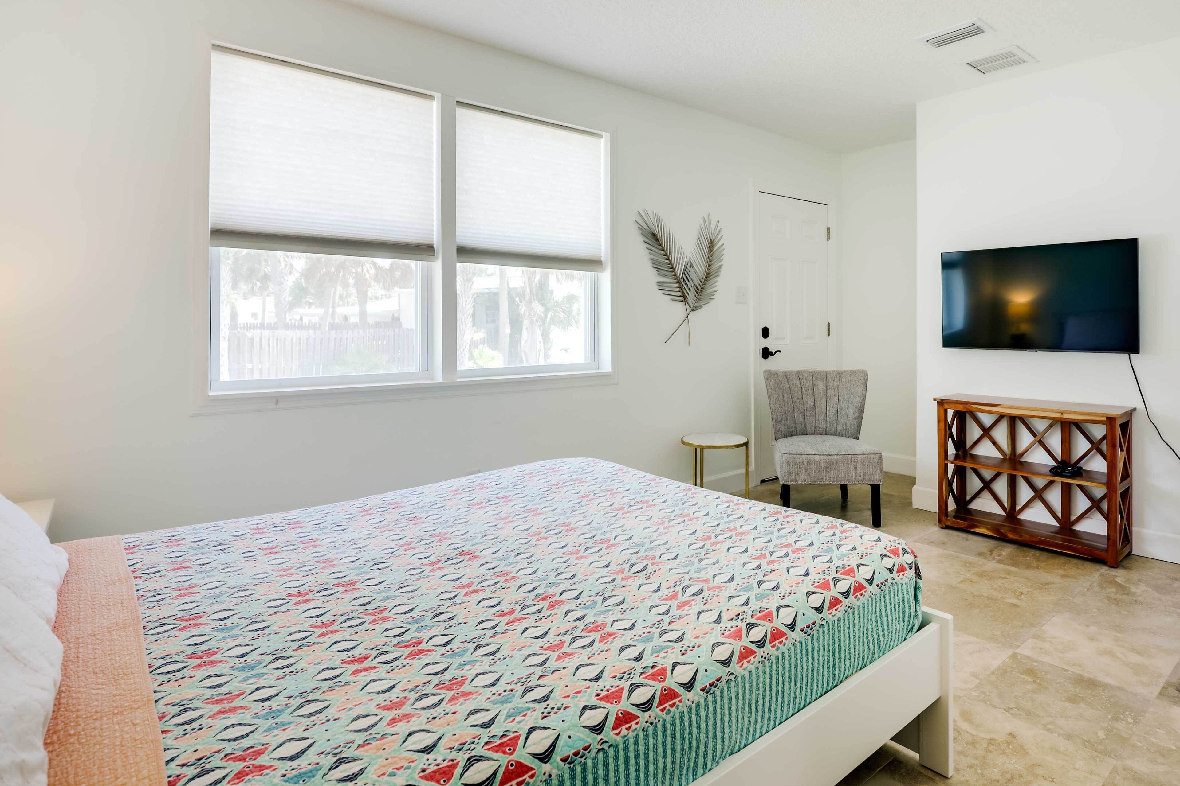 A bedroom with a bed, a chair, a TV, and a small table.