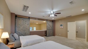 A bedroom with two beds, a ceiling fan, and a sliding barn-style door. - Houston Townhome By George Brown Convention Center (Houston)