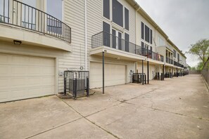 A row of townhouses with attached garages, a concrete driveway, and a metal fence. - Houston Townhome By George Brown Convention Center (Houston)