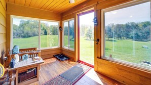 Une pièce en bois avec de grandes fenêtres, un ventilateur de plafond et un banc.