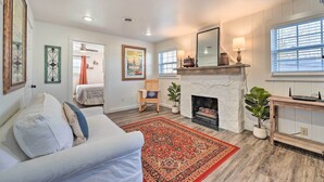 A living room with a fireplace, a sofa, a rug, and a dining area with a table and chairs. - Boho Mountain Home Escape, Walk to Marina! (Mountain Home)