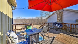 A deck with outdoor furniture, a fire pit, and a red umbrella. - Boho Mountain Home Escape, Walk to Marina! (Mountain Home)