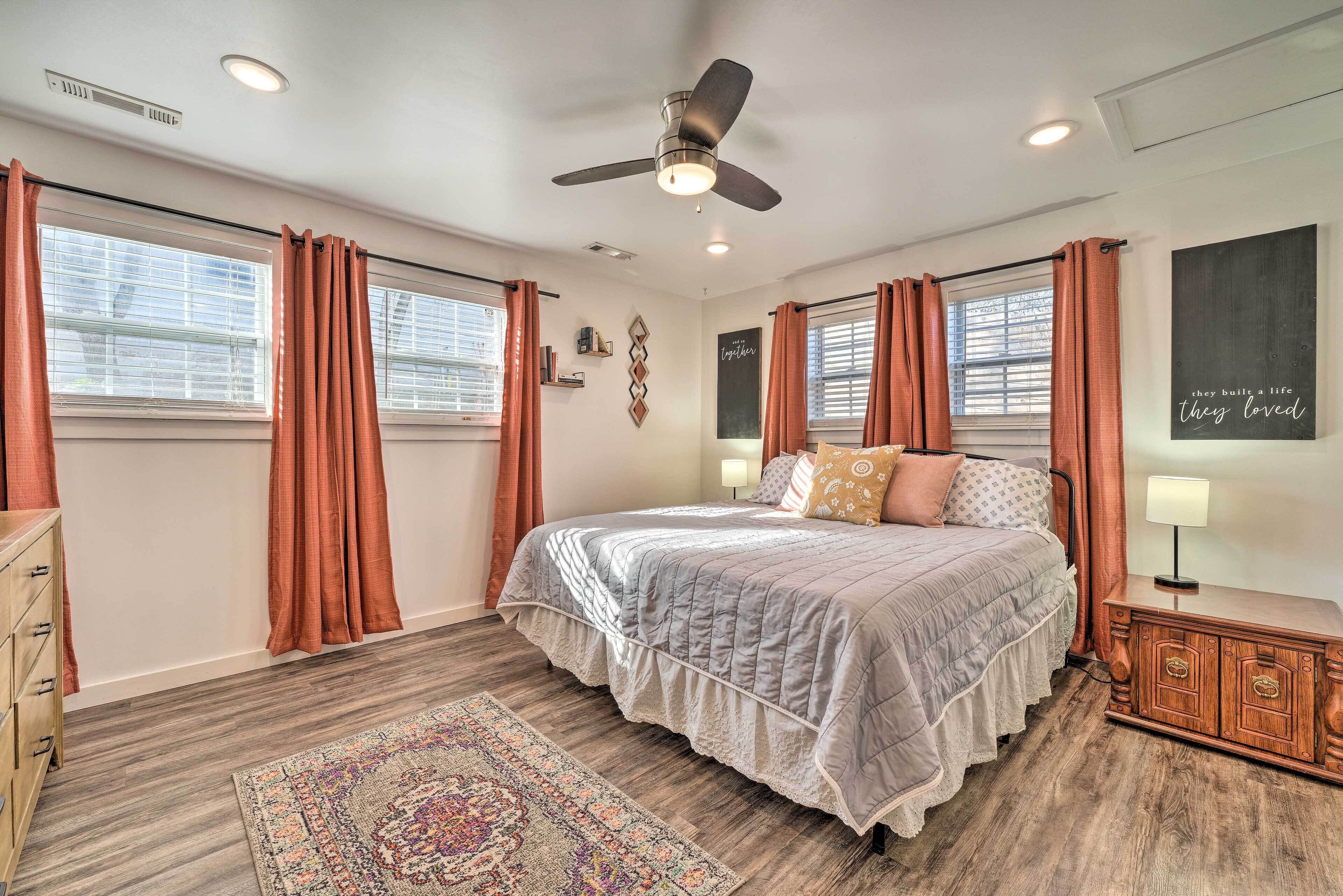 A bedroom with a bed, a ceiling fan, a nightstand, a dresser, and a rug.