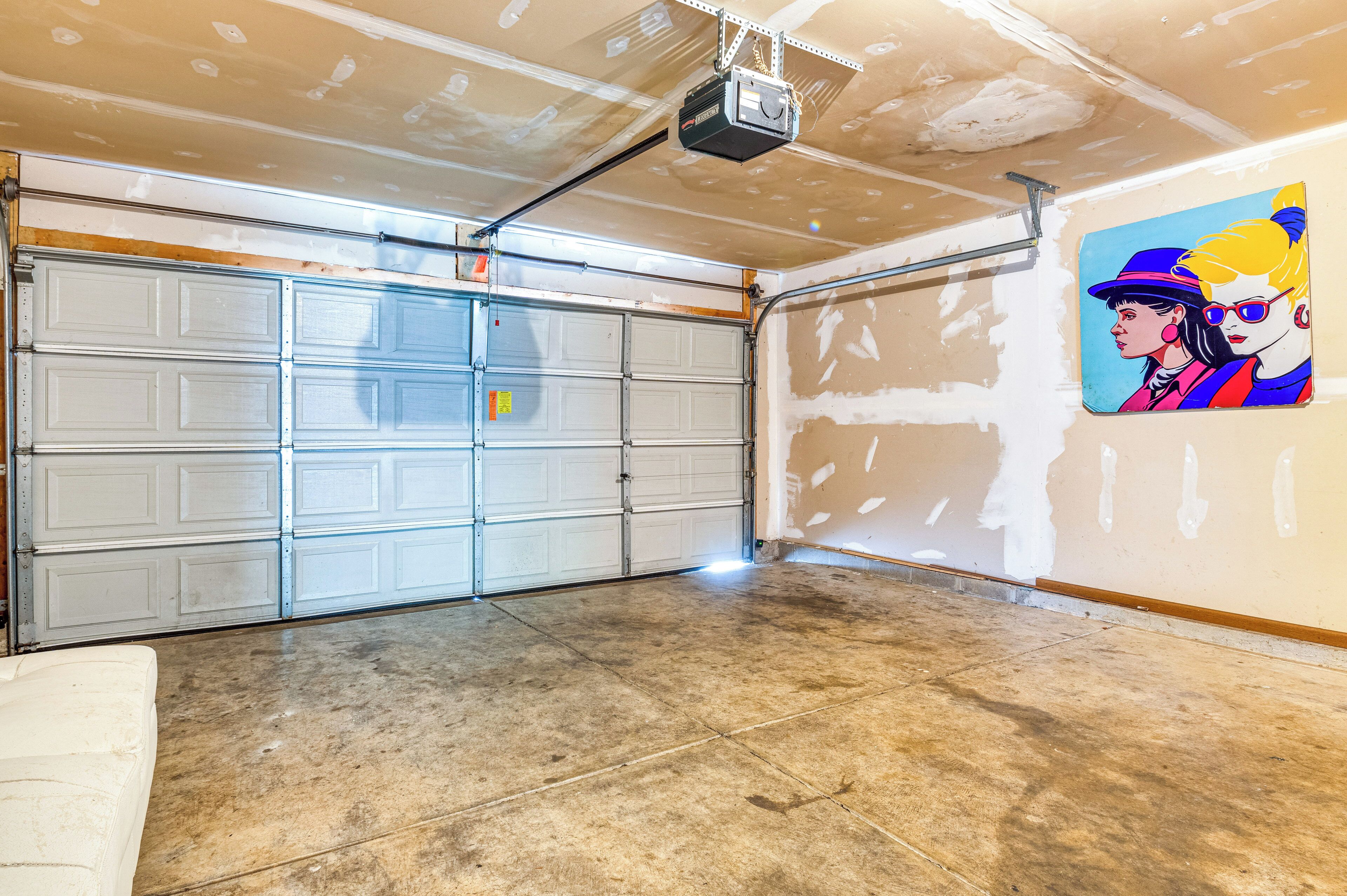 Eine Garage mit Projektor an der Decke, einer weißen Tür und einer Wand mit Wandgemälde.