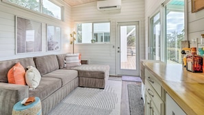 A cozy living room with a sectional sofa, a wooden ceiling, and large windows. - Updated Texas Tiny Home Rental on Lake Travis (Spicewood)