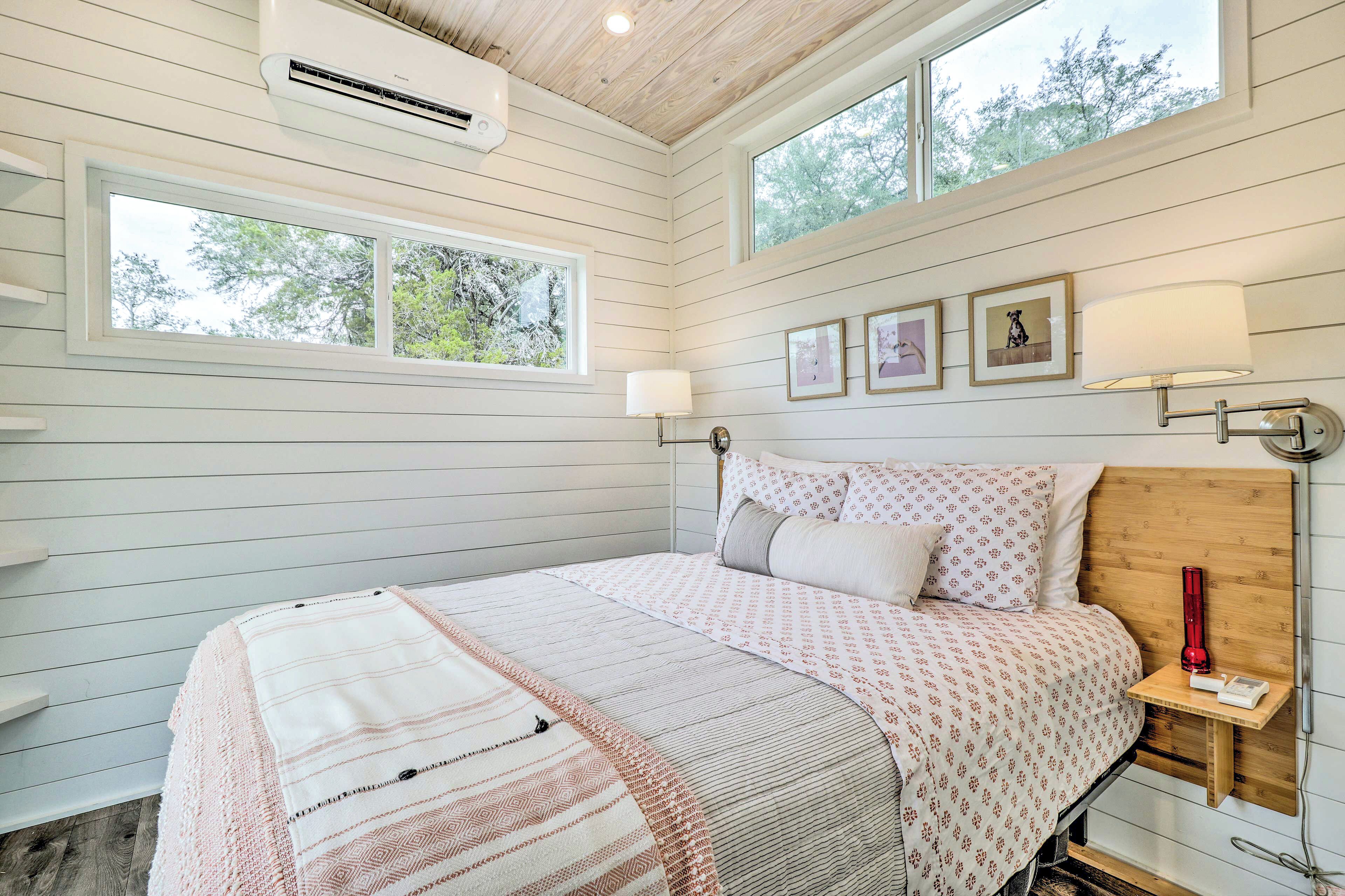 A bedroom with a bed, bedside lamps, a nightstand, and a window.