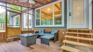 A covered porch with a table and seating area, large windows, and a door. - Lakefront Arkansas Abode - Deck, Grill & Fire Pit (Scranton)
