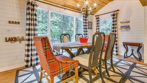A wooden interior with a dining table, plaid chairs, and a chandelier. - Lakefront Arkansas Abode - Deck, Grill & Fire Pit (Scranton)
