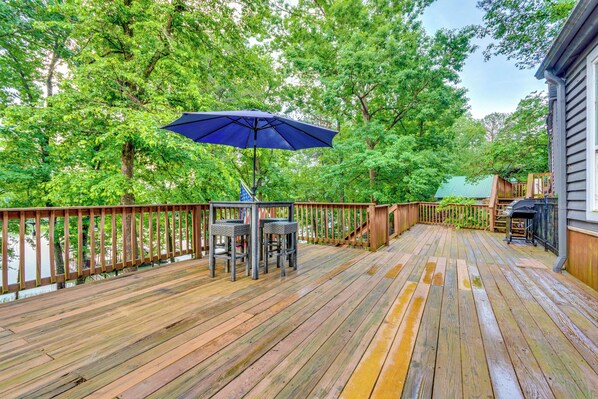 A wooden deck with a table and chairs, an umbrella, and a grill area. - Lakefront Arkansas Abode - Deck, Grill & Fire Pit (Scranton)