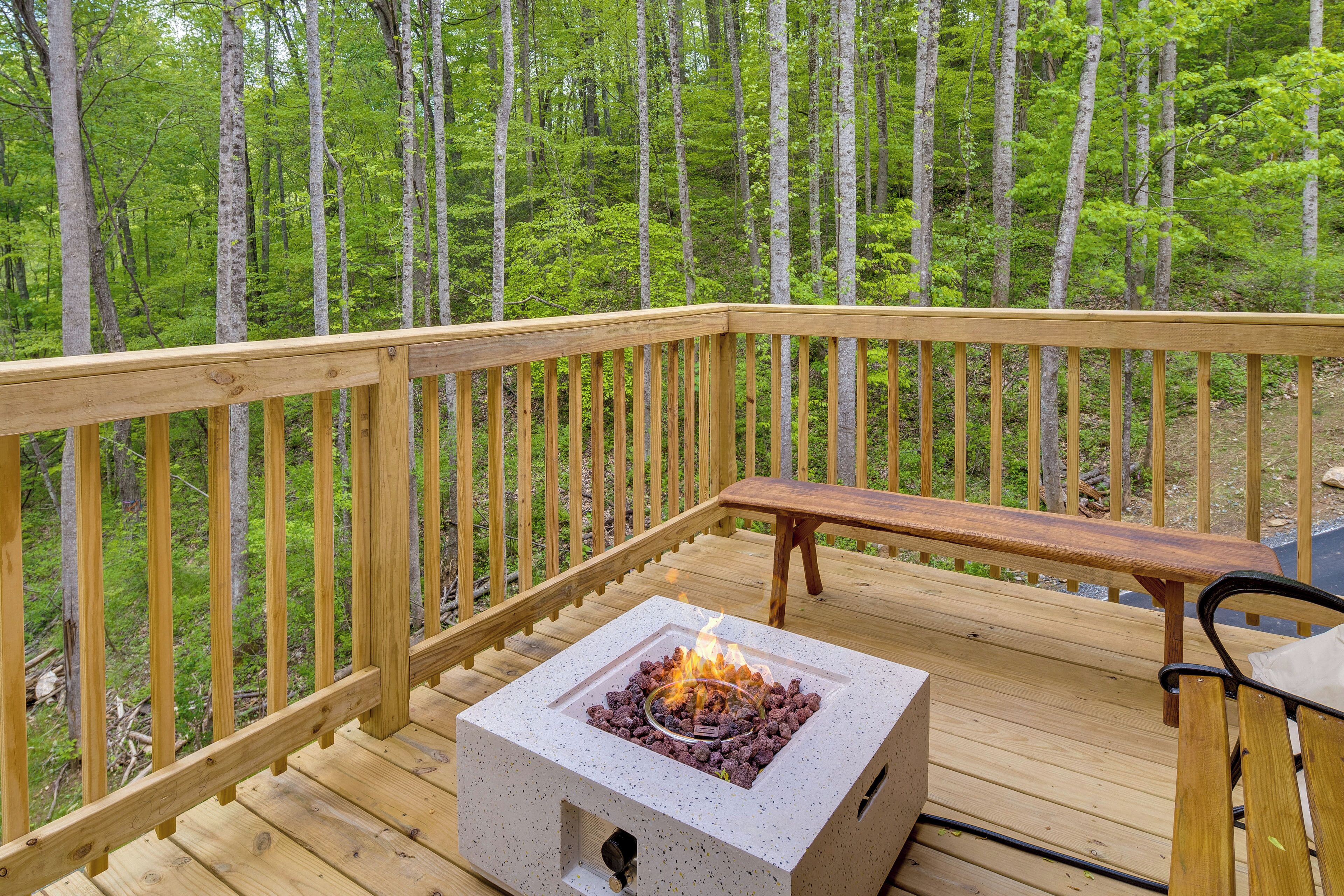 A deck with a square fire pit and a bench.