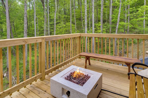 A deck with a square fire pit and a bench.