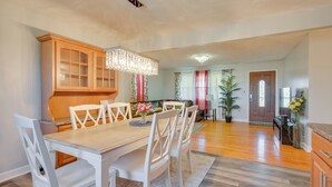 A dining area with a wooden table and white chairs, a chandelier, and a view into the living room. - Deck & Grill: Convenient Home in Hummelstown (Hershey)