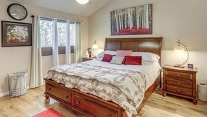 Un dormitorio con una cama, una mesita de noche, un aparador, un ventilador de techo, un reloj y una ventana con cortinas.