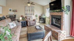 Una sala de estar con chimenea, un sofá, una mesa de centro y una televisión.