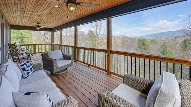 A wooden deck with wicker furniture and a view of mountains. - Smoky Mountain Cabin Rental: Game Room, Fire Pit! (Andrews)