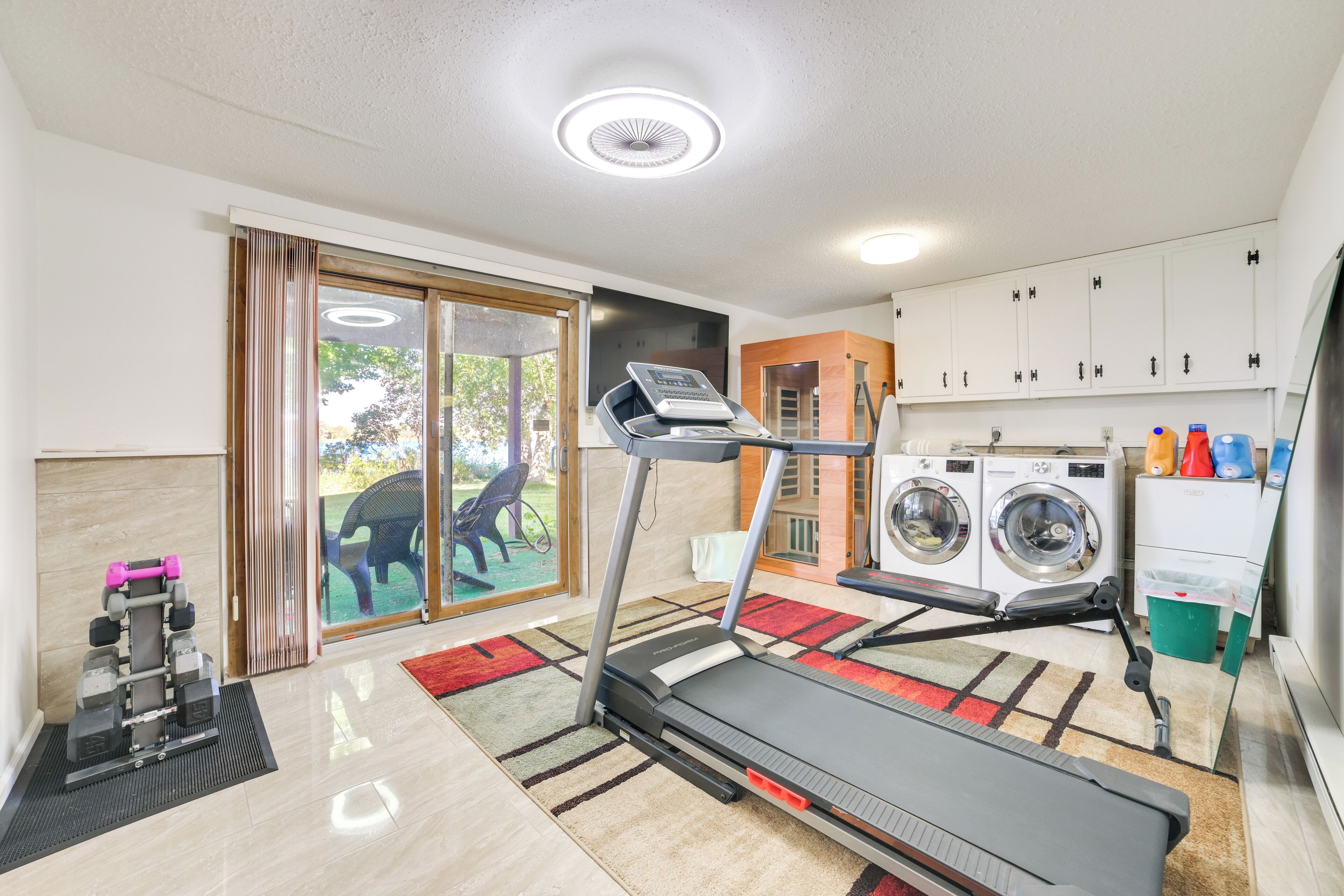 A home gym with a treadmill, weights, and a washing machine.