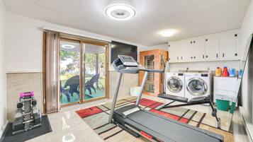 A home gym with a treadmill, weights, and a washing machine.
