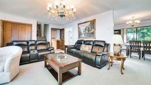 A spacious living room with leather sofas, a coffee table, and a chandelier. - Riverfront Sault Ste Marie Home w/ Dock! (Sault Ste. Marie)