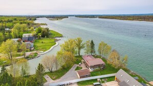 A riverside property with a house, a dock, and a grassy area. - Riverfront Sault Ste Marie Home w/ Dock! (Sault Ste. Marie)