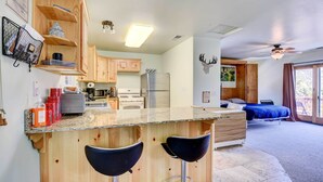 Una cucina moderna con mobili in legno, un piano di lavoro in granito e due sgabelli neri.
