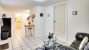 A living room with a glass coffee table, a leather sofa, and a dining area with a wooden table and chairs. - Lakeland Vacation Rental: 38 Mi to Disney! (Lakeland)