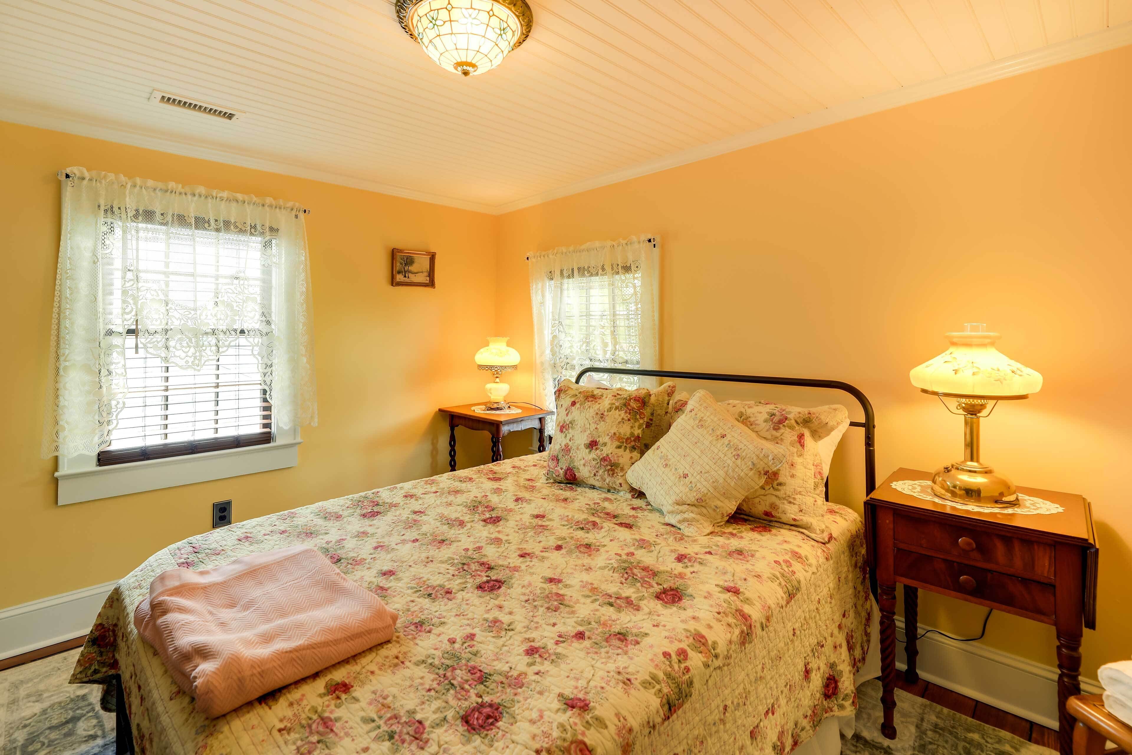Une chambre à coucher avec une couvre-lit à motifs floraux, deux lampes de chevet et une table de chevet en bois.