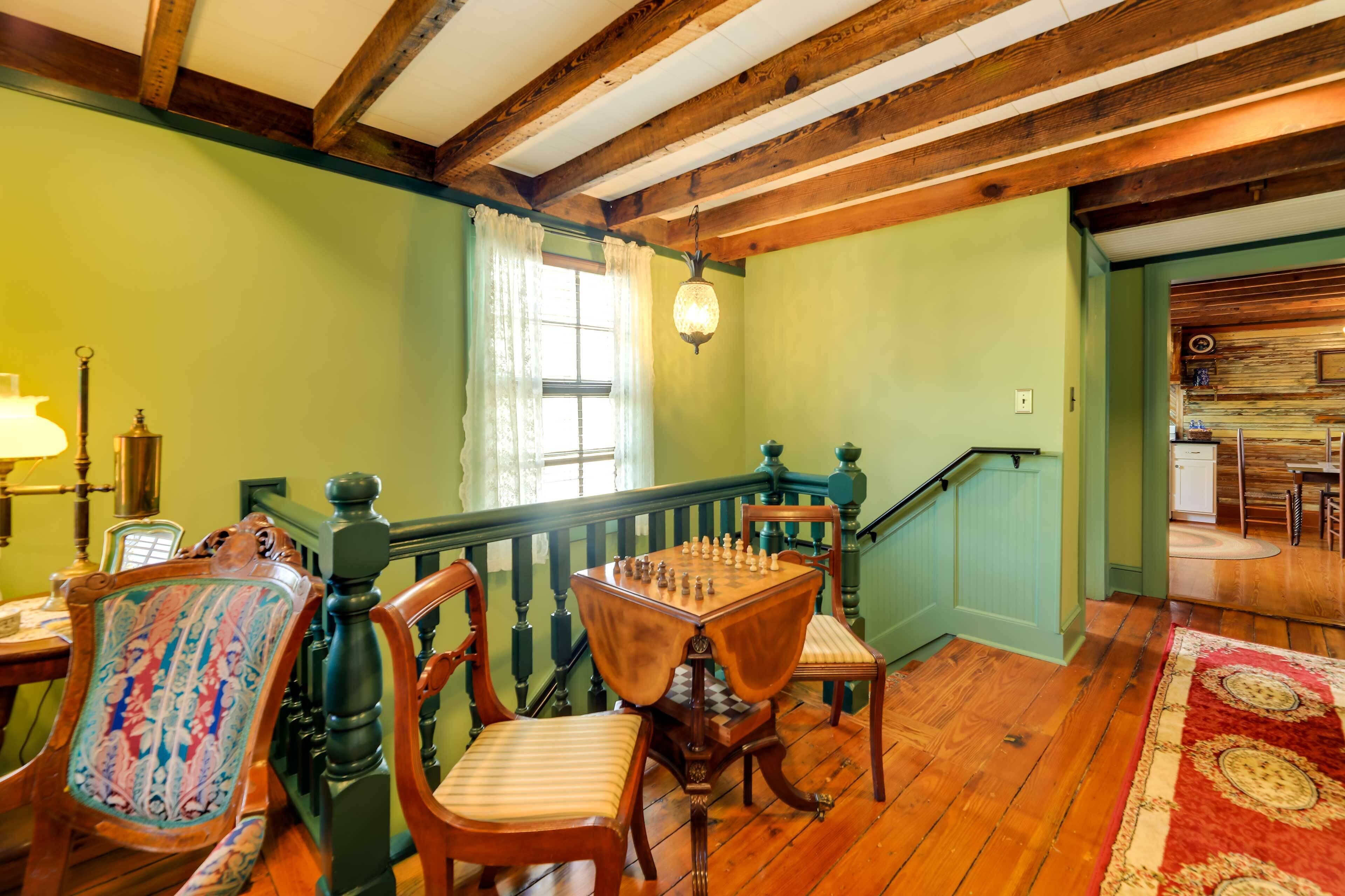 A room with a wooden floor, a chess table, and two chairs with patterned upholstery.