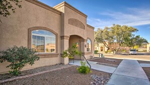 A building with a stucco exterior, large windows, and a landscaped front yard with a sidewalk and a parked car. - Green Valley Studio in 55+ Community! (Green Valley)