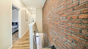 A hallway with a wooden floor, a brick wall, and a white railing. - Pittsburgh Townhome: 1 Mi to Downtown (Pittsburgh)