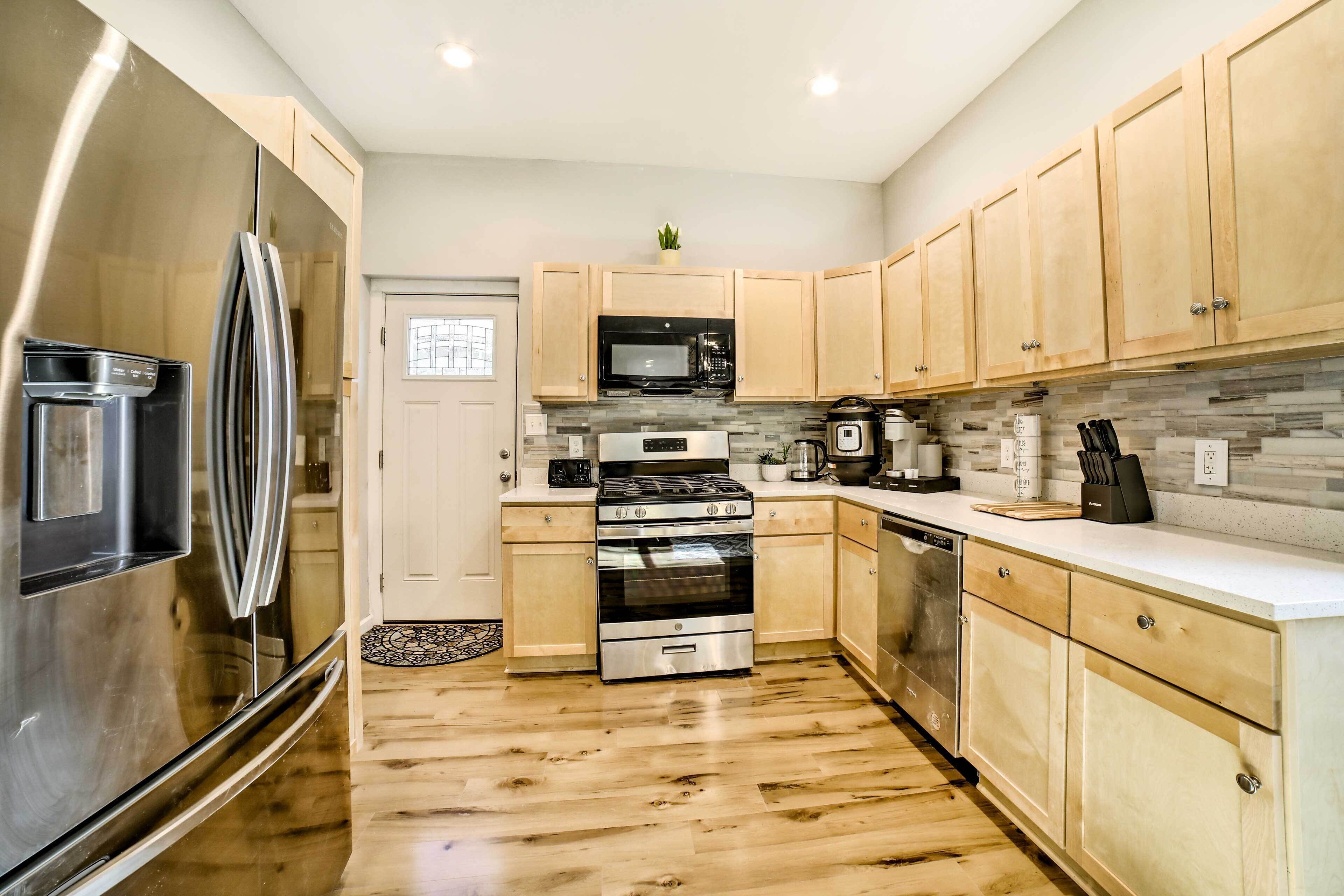 A modern kitchen with stainless steel appliances, wooden cabinets, and a tiled backsplash.