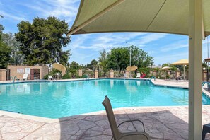 A swimming pool with lounge chairs and umbrellas, surrounded by trees and a building with a sign. - Arizona Getaway ~ 3 Mi to Old Town Scottsdale (Scottsdale)