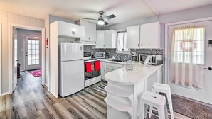 A modern kitchen with white cabinetry, a central island, and a ceiling fan. - Tobyhanna Home Near Kalahari w/ Lake & Pool Access (Tobyhanna)