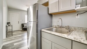 A modern kitchen with a stainless steel refrigerator, a granite countertop, and white cabinetry.