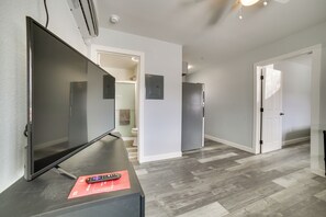 A modern living room with a flat-screen TV, a remote control, and a red mat on a dark wooden table. - Updated Hawthorne Apartment, 12 Mi to Walker Lake! (Hawthorne)
