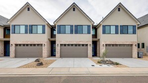 A row of three modern two-story houses with brick foundations and grey roofs, each with a garage door and a small landscaped area in front. - Modern Santa Clara Vacation Rental w/ Patio (Santa Clara)
