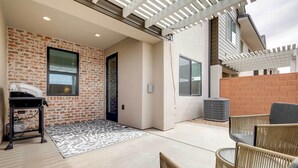 A covered patio area with a brick wall, a door, and a seating area with wicker furniture. - Modern Santa Clara Vacation Rental w/ Patio (Santa Clara)