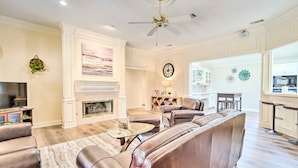A spacious living room with a fireplace, leather sofas, a coffee table, and a television. - Lubbock Home w/ Patio ~ 6 Mi to Texas Tech! (Lubbock)