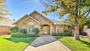 A two-story house with a brick facade, a front entrance, and a well-maintained lawn. - Lubbock Home w/ Patio ~ 6 Mi to Texas Tech! (Lubbock)