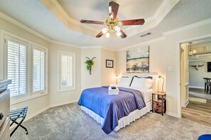 Quarto com cama, ventilador de teto e mesa de cabeceira.