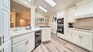 A modern kitchen with white cabinetry, a central island, built-in appliances, and a skylight. - Lubbock Home w/ Patio ~ 6 Mi to Texas Tech! (Lubbock)
