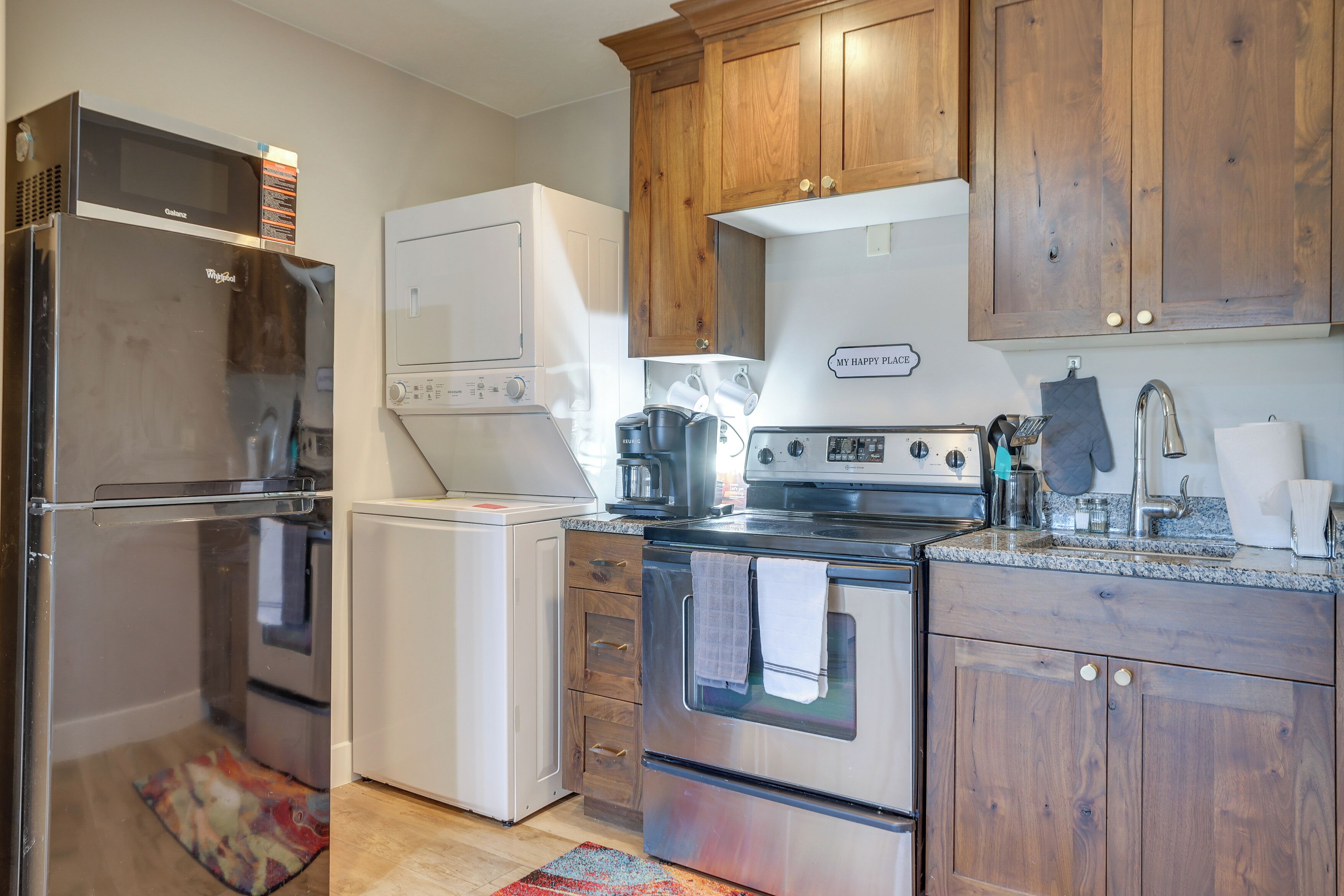 A kitchen with wooden cabinets, a stainless steel refrigerator, a built-in oven, and a microwave.